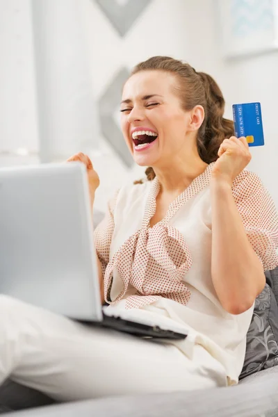 Счастливая молодая женщина с кредитной картой и ноутбуком радуется — стоковое фото
