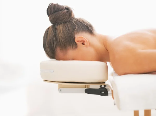 Relaxado jovem mulher que coloca na mesa de massagem — Fotografia de Stock