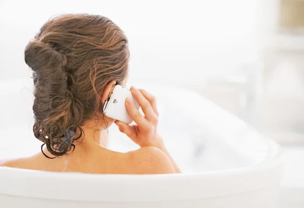 Young woman in bathtub talking cell phone — Stock Photo, Image