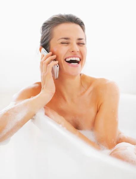 Happy young woman talking cell phone in bathtub — Stock Photo, Image