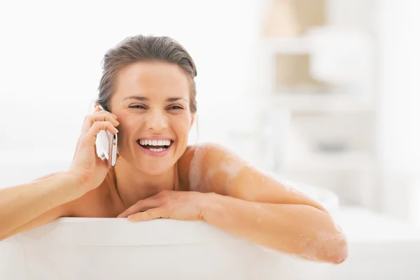 Sonriente mujer joven hablando de teléfono móvil en la bañera — Foto de Stock