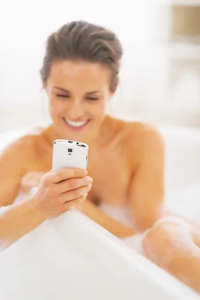 Primer plano de la mujer joven escribiendo sms en la bañera —  Fotos de Stock