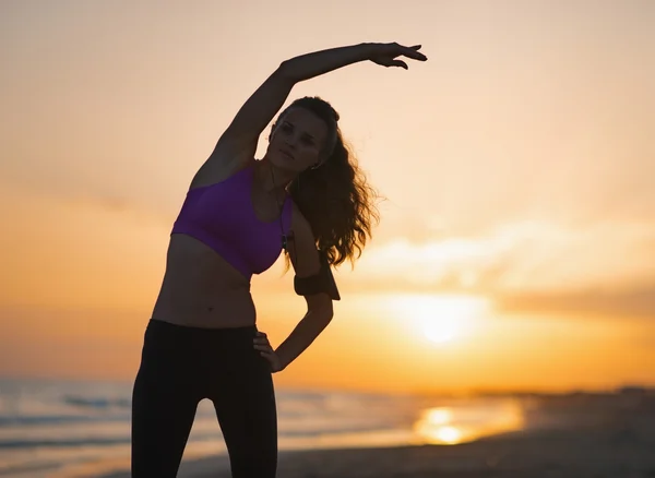 Silueta de fitness joven mujer estirándose en la playa al atardecer —  Fotos de Stock