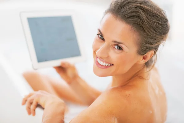 Mujer joven sonriente usando tableta pc en la bañera —  Fotos de Stock