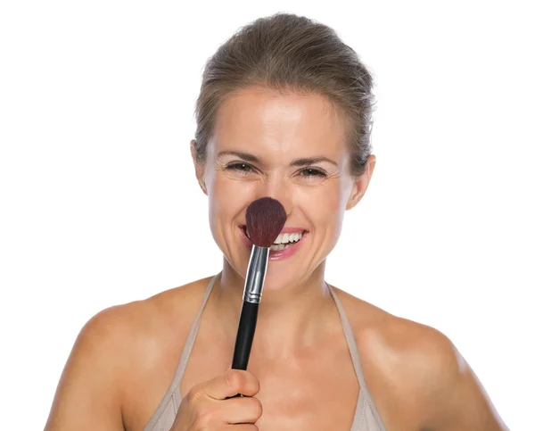 Smiling young woman touching nose with brush — Stock Photo, Image