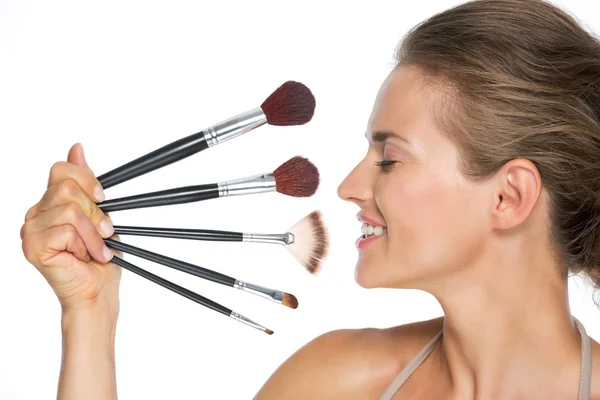 Profile portrait of happy young woman with makeup brushes — Stock Photo, Image