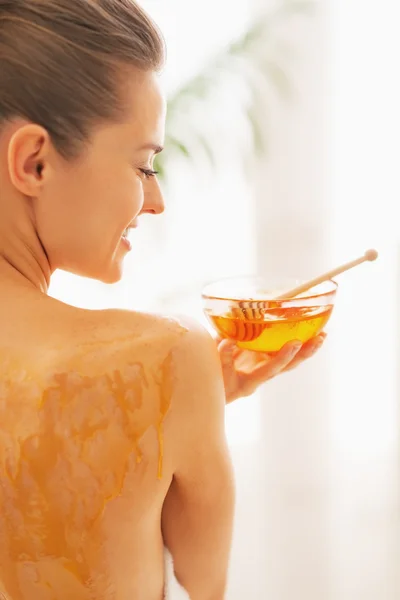 Smiling young woman holding plate with honey — Stock Photo, Image