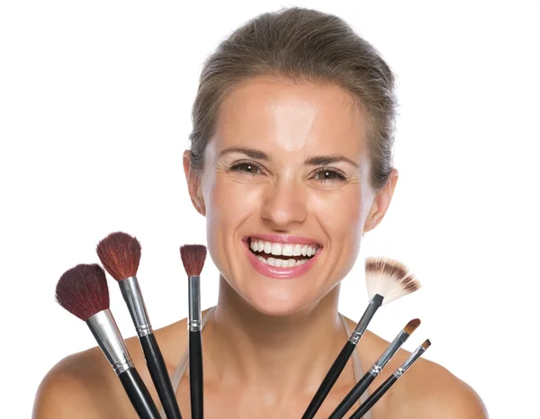 Улыбающаяся молодая женщина с кисточками для макияжа — стоковое фото