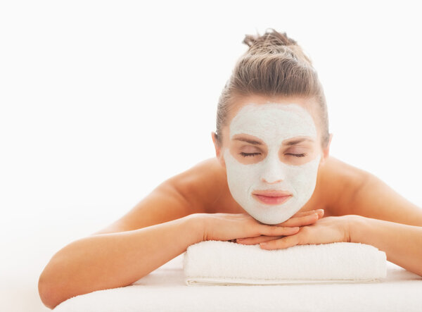 Relaxed young woman with revitalising mask on face laying on massage table