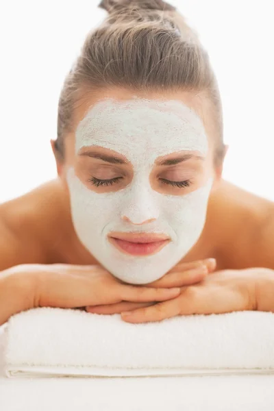 Jeune femme avec masque revitalisant sur le visage posé sur une table de massage — Photo