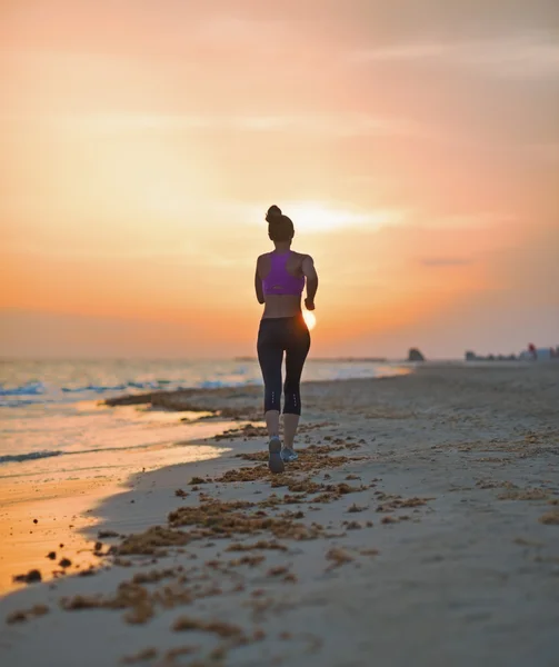 Fitness junge Frau läuft abends am Strand — Stockfoto