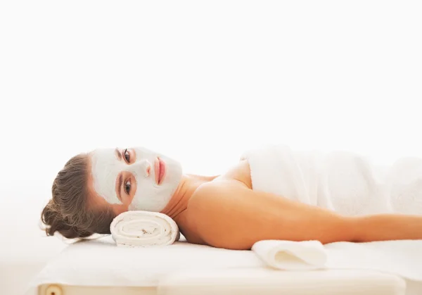 Portrait of happy young woman with revitalising mask on face laying on massage table — Stock Photo, Image