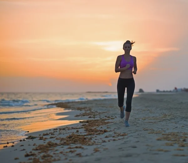 Fitness junge Frau läuft abends am Strand — Stockfoto
