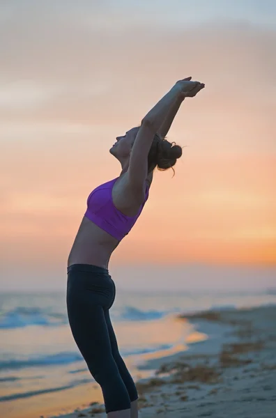 Fitness young woman making exercise on beach in the evening — Stock Photo, Image