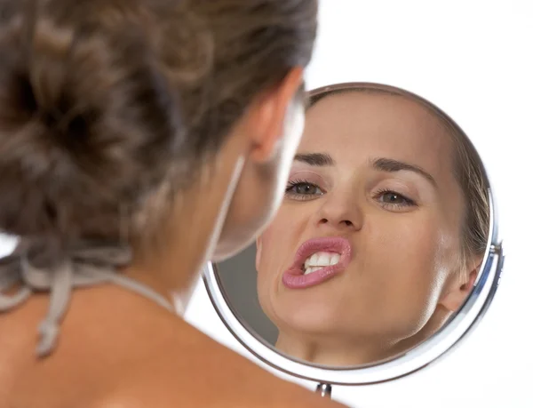 Young woman making funny faces while looking in mirror — Stock Photo, Image