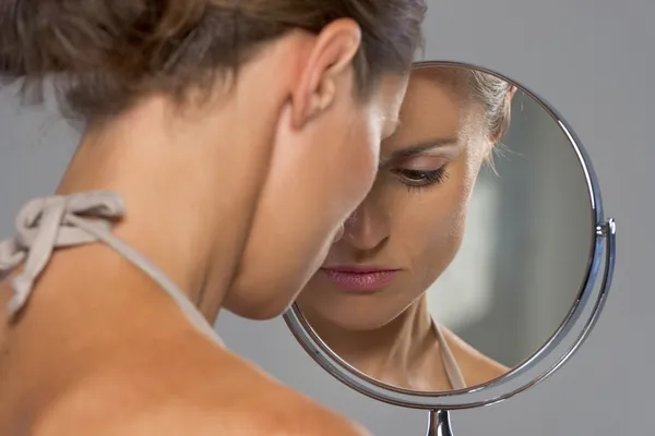 Наголошена молода жінка дивиться у дзеркало — стокове фото