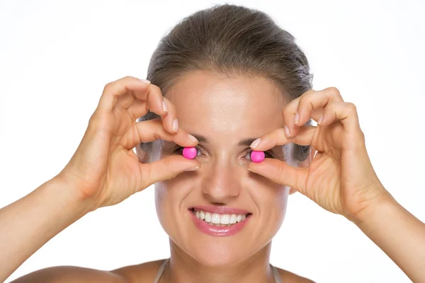 Jovem mulher segurando pílulas na frente dos olhos — Fotografia de Stock