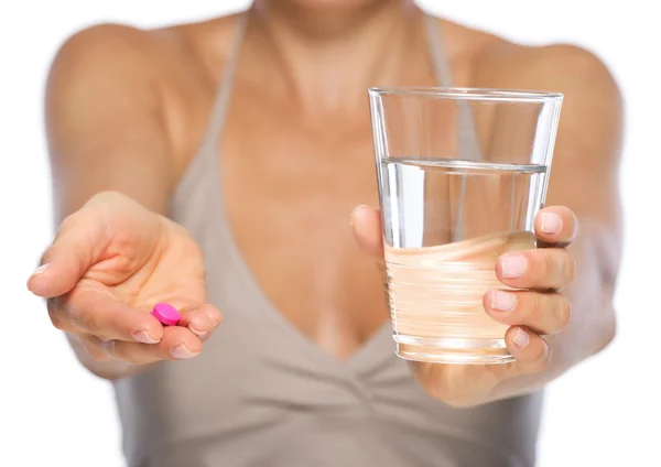 Primer plano de la mujer joven dando píldora y vaso de agua — Foto de Stock