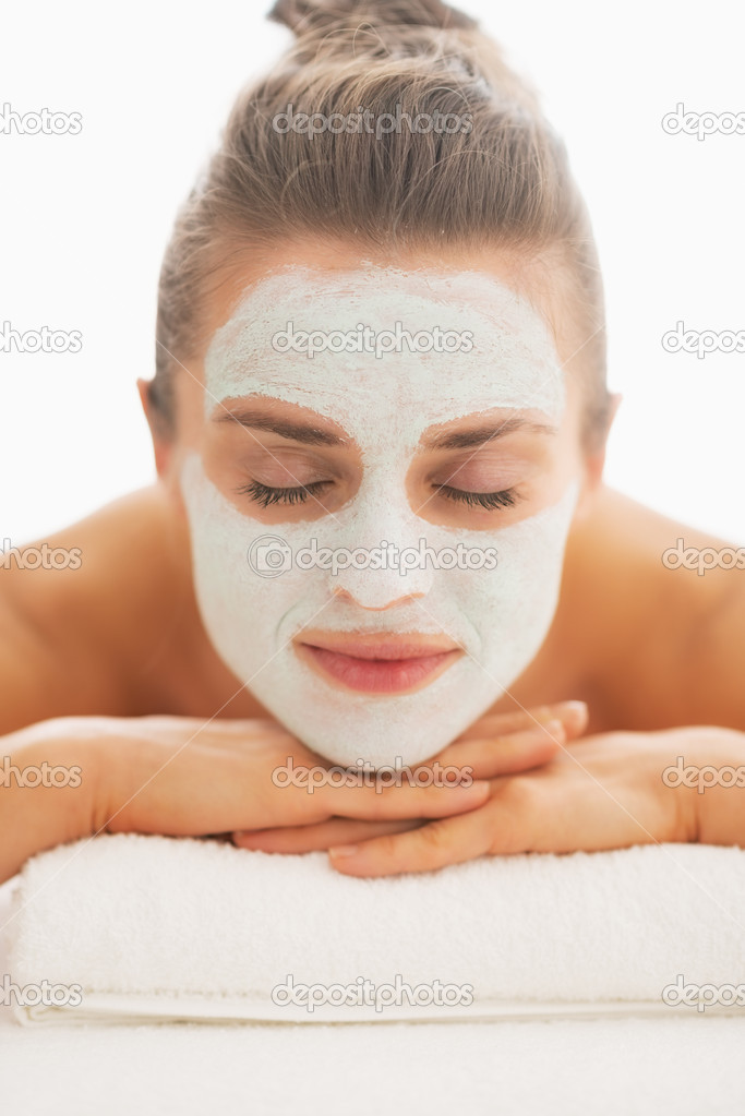 Young woman with revitalising mask on face laying on massage table