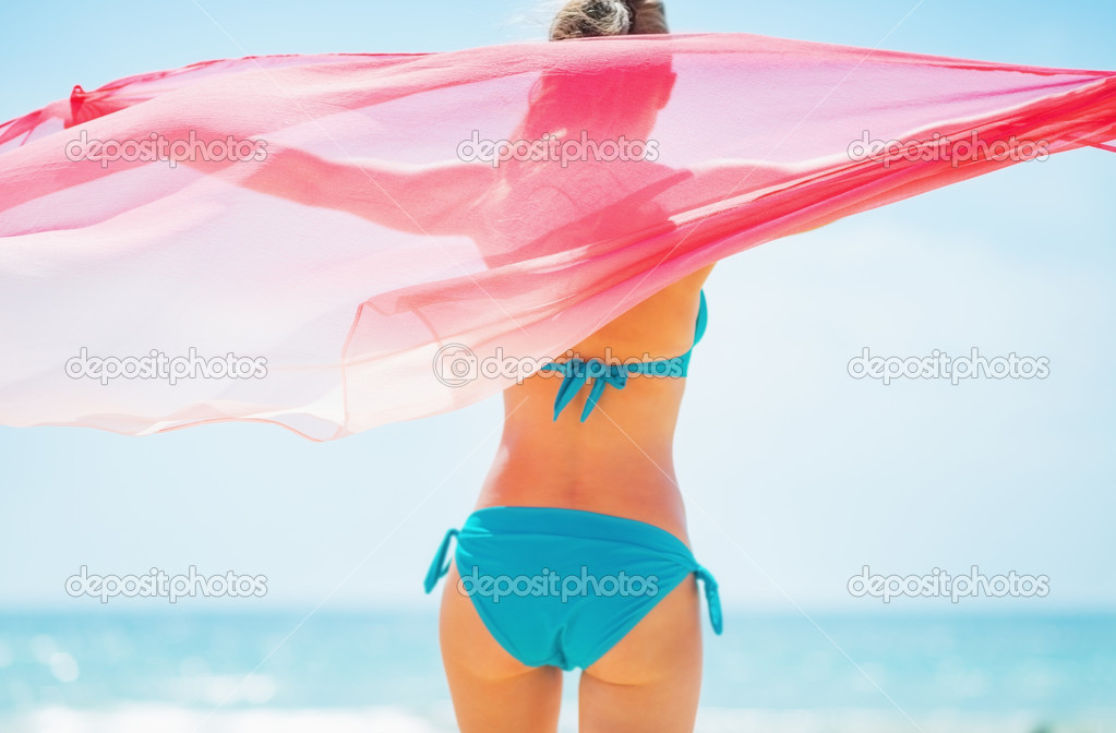 Young woman with parero rejoicing on beach.