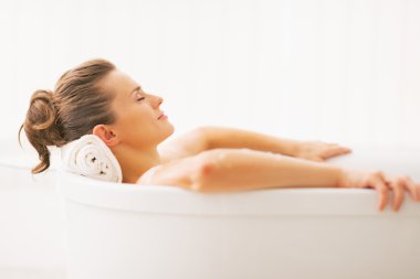 Portrait of young woman relaxing in bathtub clipart