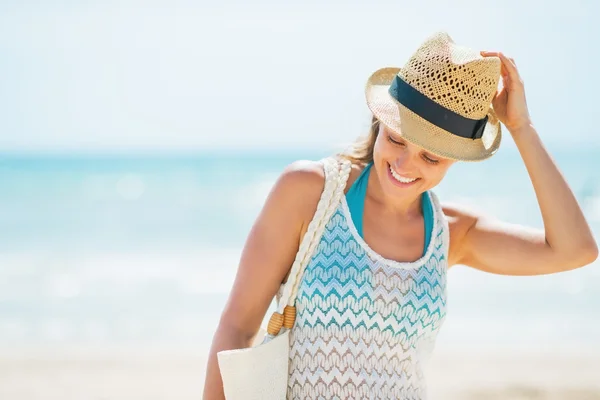 Glimlachende jonge vrouw met hoed op strand — Stockfoto