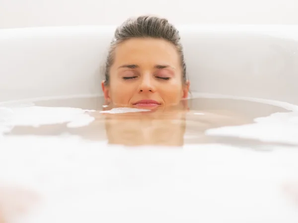 Junge Frau liegt unter Wasser in Badewanne — Stockfoto