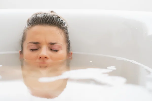 Stressed young woman laying under water in bathtub — Stock Photo, Image