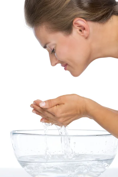 Young woman washing face in glass bowl with water — Stock Photo, Image