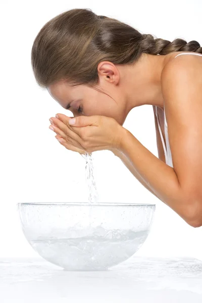 Porträt einer jungen Frau, die ihr Gesicht in einer Glasschale mit Wasser wäscht — Stockfoto