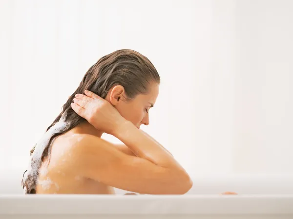 Jovem mulher lavando o cabelo na banheira — Fotografia de Stock