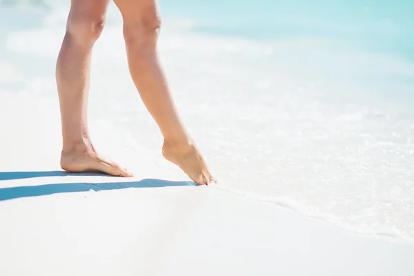 Nahaufnahme einer jungen Frau, die am Meer Wasser mit dem Bein berührt — Stockfoto