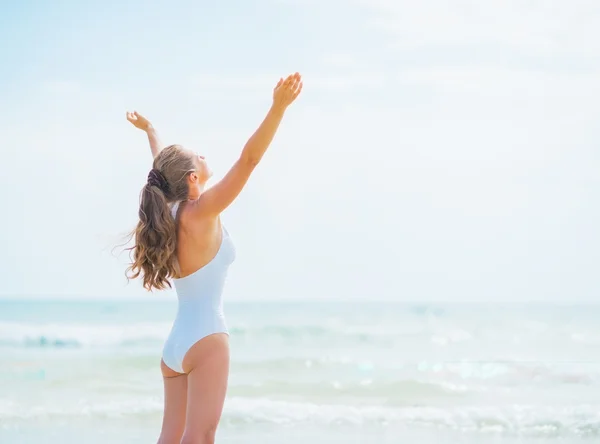 Happy young woman in swimsuit rejoicing on sea shore — Stock Photo, Image