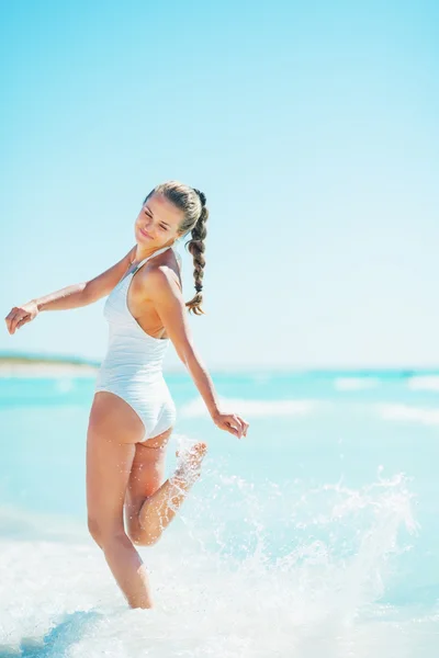 Lachende jonge vrouw spelen met golven op strand — Stockfoto