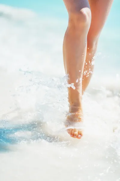 Nahaufnahme einer jungen Frau, die am Strand mit Wellen spielt — Stockfoto