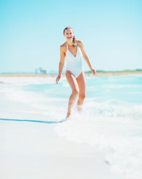 Leende ung kvinna leker med vågor på stranden — Stockfoto