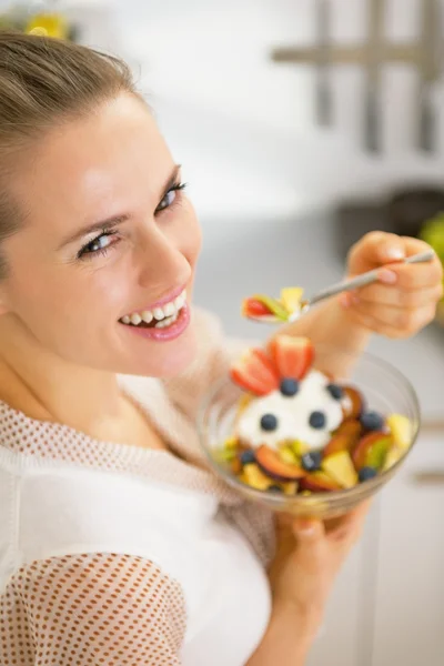 Lachende jonge huisvrouw eten van verse fruitsalade — Stockfoto