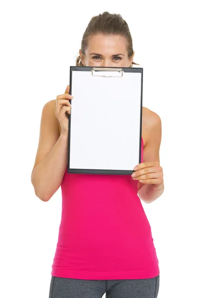 Fitness young woman hiding behind blank clipboard — Stock Photo, Image