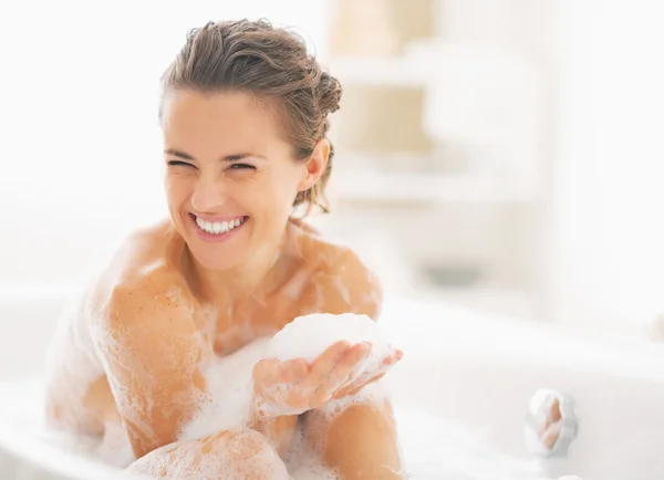 Портрет счастливой молодой женщины, играющей с пеной в ванной — стоковое фото