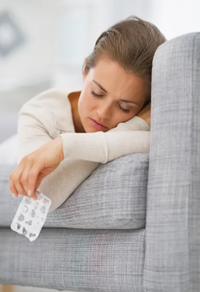 Calm young housewife with blister package laying on divan — Stock Photo, Image