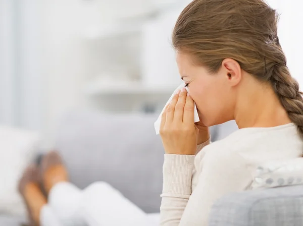 Jonge vrouw sofa opleggen en blazen neus — Stockfoto