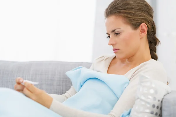 Displeased young woman looking on thermometer — Stock Photo, Image