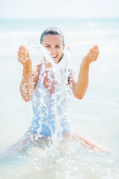 Mujer joven en traje de baño jugando con agua de mar — Foto de Stock