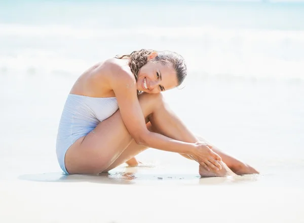 海の海岸に座っている水着で若い女性の笑みを浮かべてください。 — ストック写真