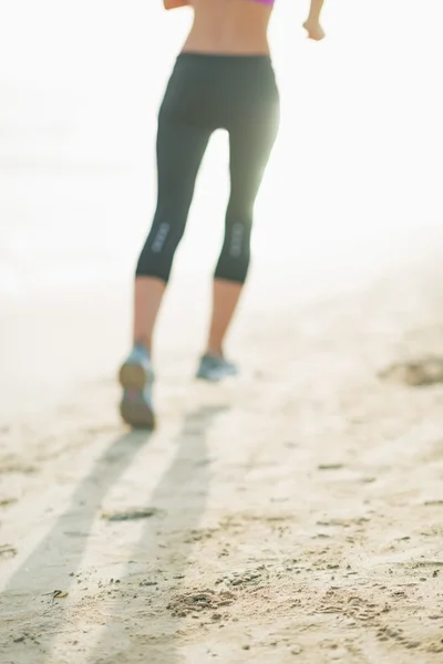 Närbild på fitness ung kvinna kör på stranden — Stockfoto