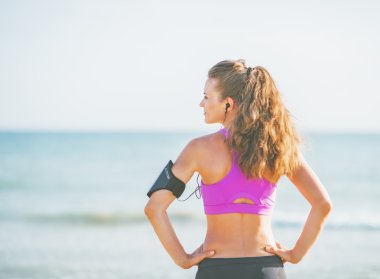 Sahilde duran ve üzerinde kopya alanı arıyor genç kadın fitness.