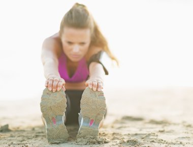 closeup fitness genç kadını kumsalda germe