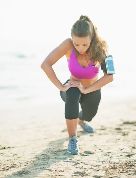 Fitness jovem mulher se alongando na praia — Fotografia de Stock