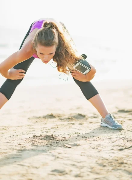 Fitness giovane donna che si estende sulla spiaggia — Foto Stock