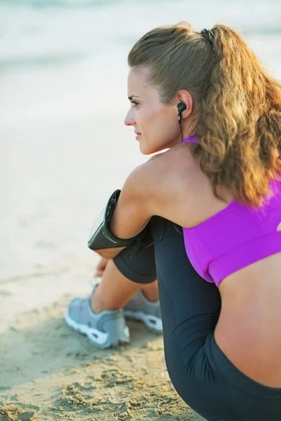 Healthy young woman sitting on beach — Stock Photo, Image